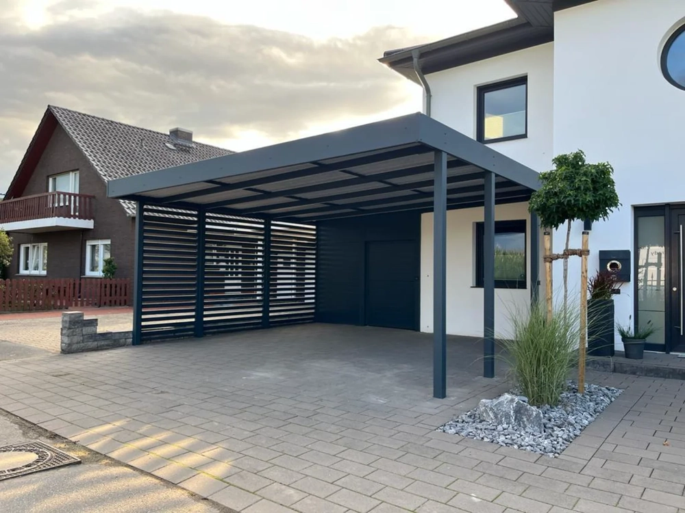 Moderner freistehender Carport aus anthrazitfarbenem Metall an Einfamilienhaus mit gepflasterter Auffahrt