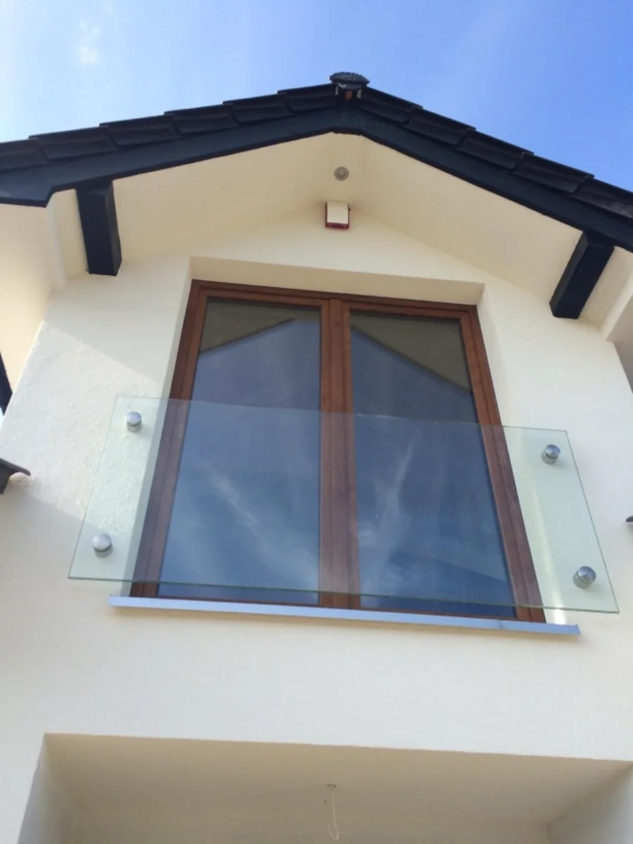 Glasgeländer an kleinem Balkonfenster in moderner Hausfassade mit Holzrahmen und Pultdach