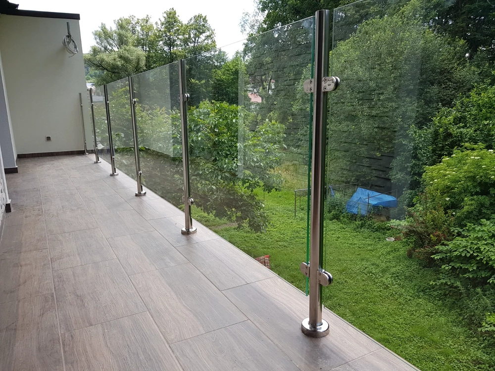 Moderner Balkon mit Glasgeländer auf Edelstahlpfosten und holzoptischen Bodenfliesen