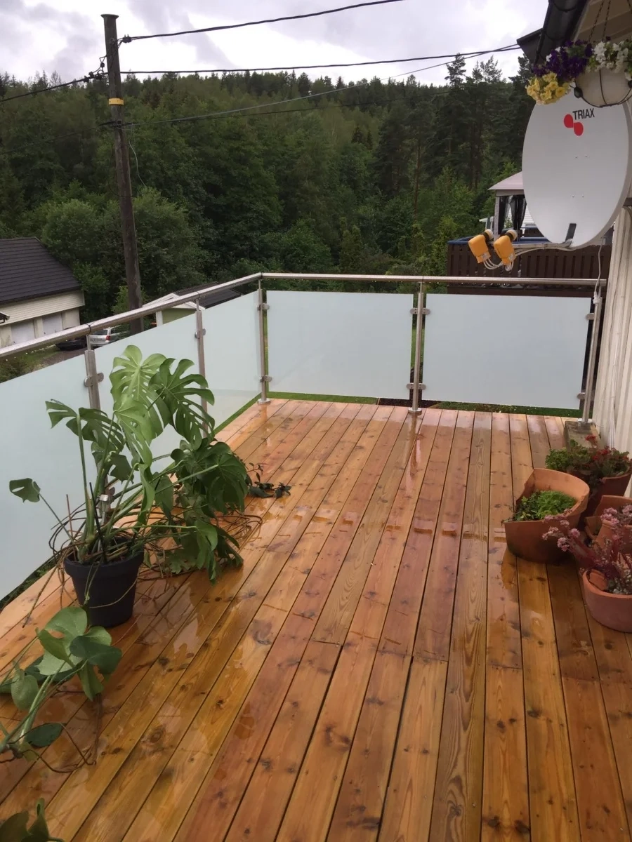 Terrassengeländer mit satiniertem Glas auf einer Holzterrasse mit Topfpflanzen