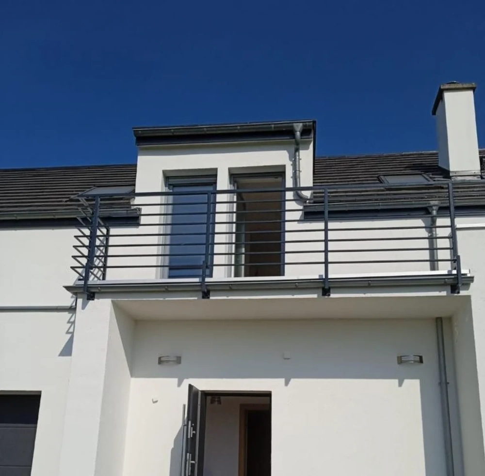 Moderner Balkongeländer aus grauem Metall an weißer Fassade eines Einfamilienhauses