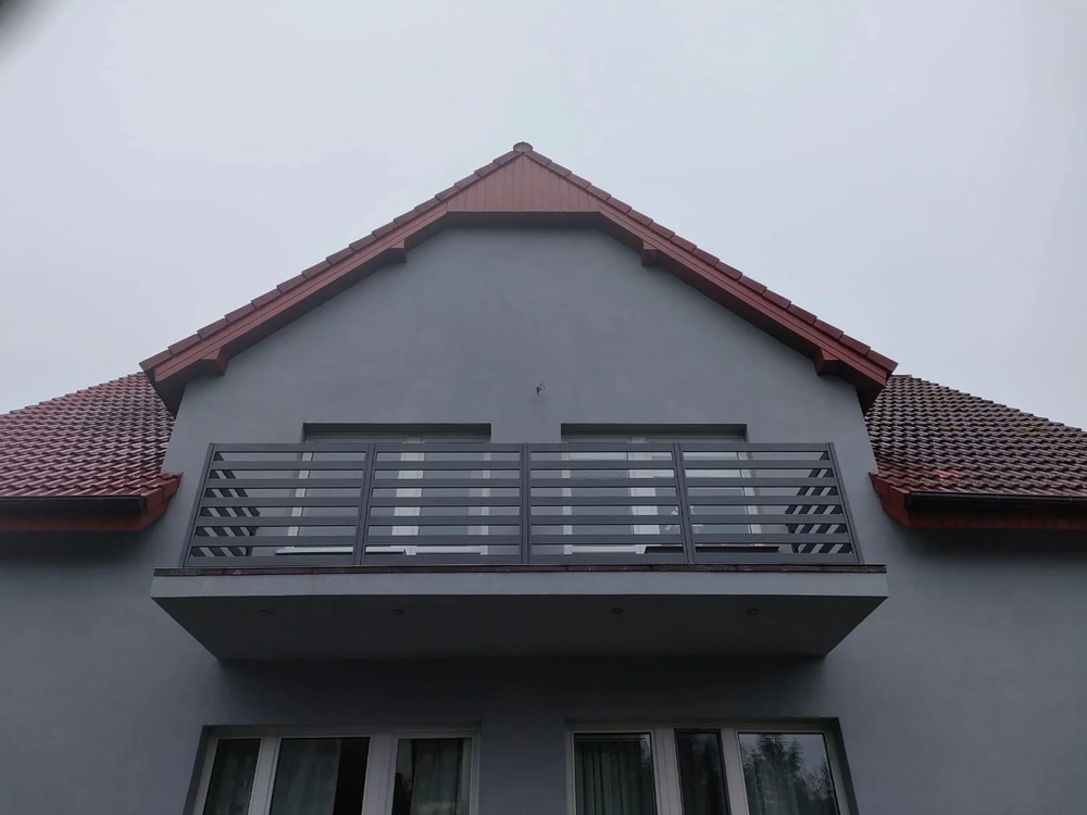 Moderner Balkon vor grauer Fassade mit pulverbeschichtetem Metall-Balkongeländer mit waagerechten Streben