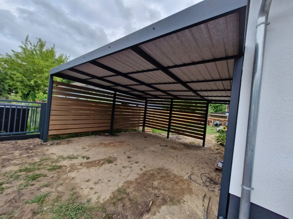 Überdachter Carport mit pulverbeschichtetem Metallrahmen und waagerechten Holzlamellen an Hausseite