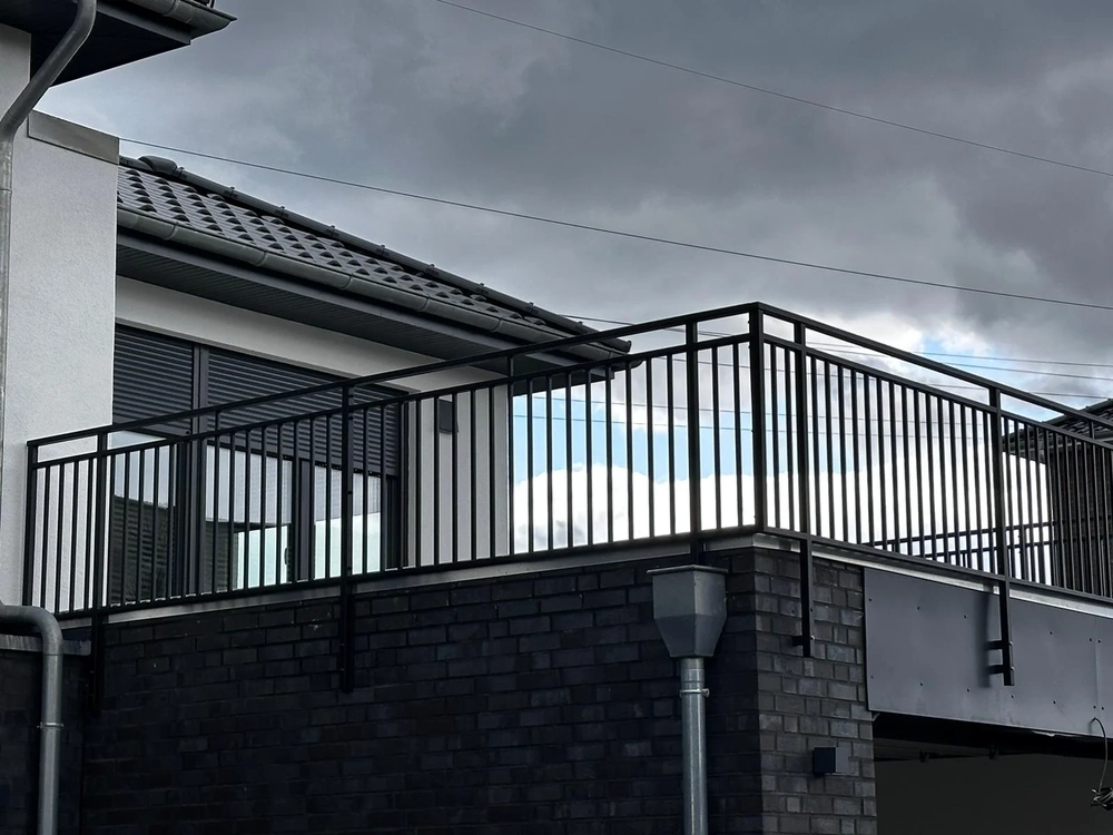 Schwarzes Balkongeländer aus Metall an moderner Fassade bei bewölktem Himmel